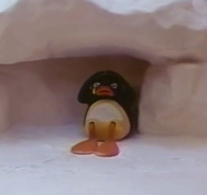 Imagem do personagem Pingu (um pinguim, personagem principal de um programa homônimo, em stop motion), sentado sob uma camada de neve, com as mãos na cabeça e chorando. 