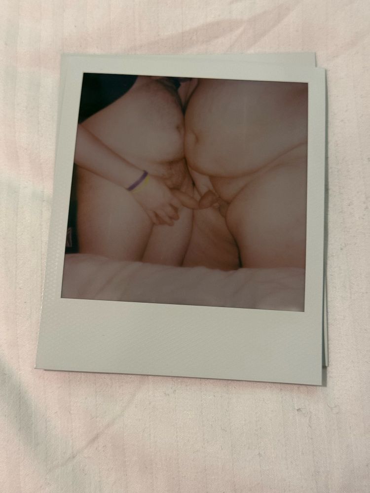 A Polaroid photos showing two guys stood together with their uncut dicks touching