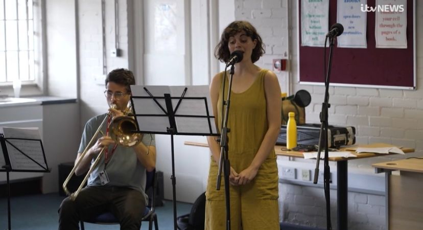 An image of a woman singing into a microphone and a man playing the trombone