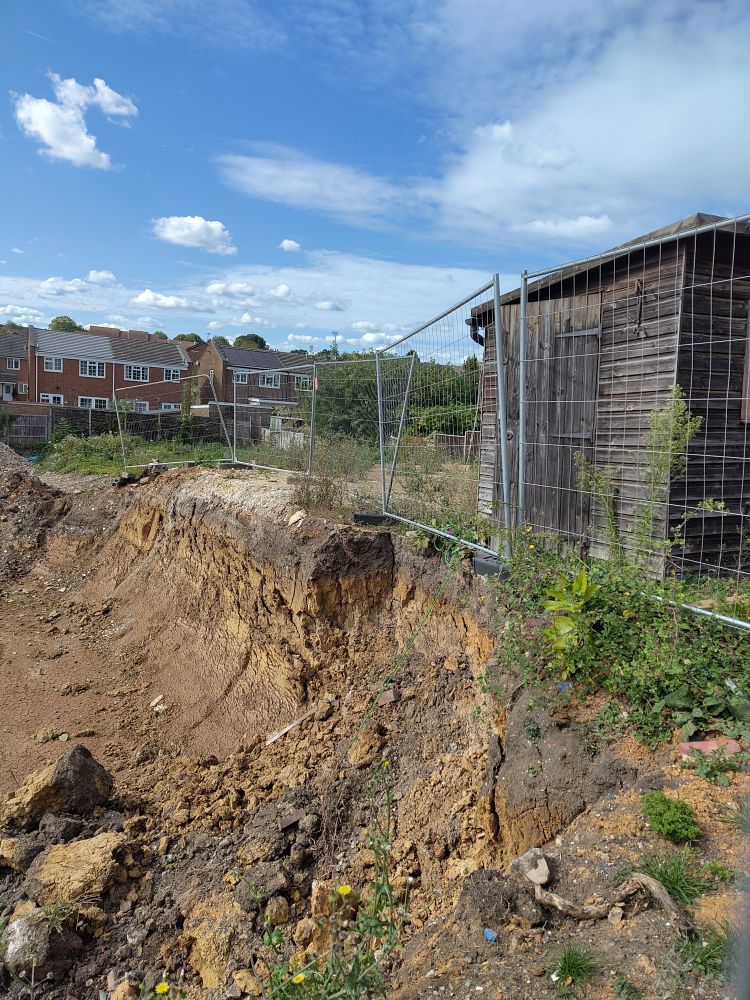 fence next to crumbling pit of dirt