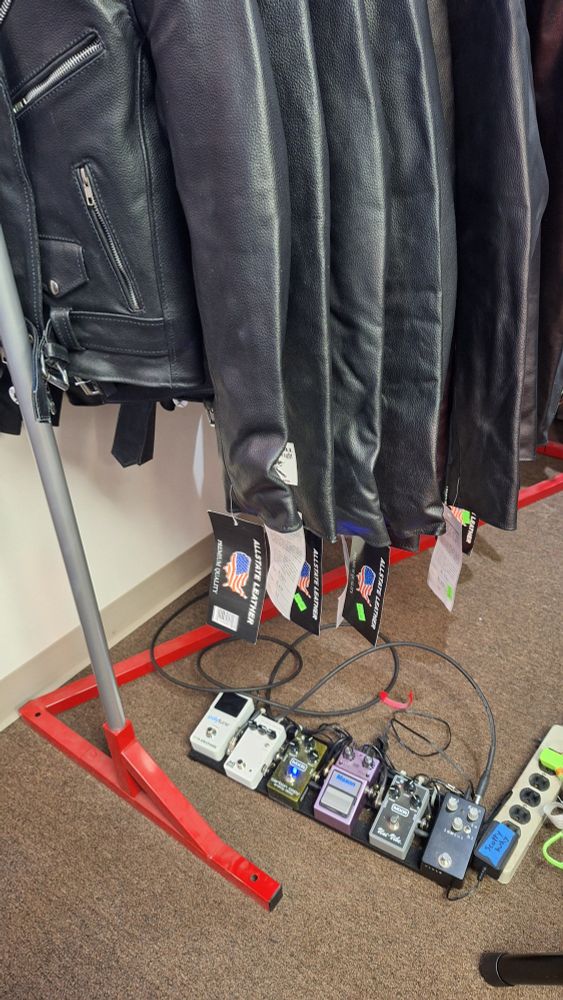 A rack of leather jackets and a guitar pedal board
