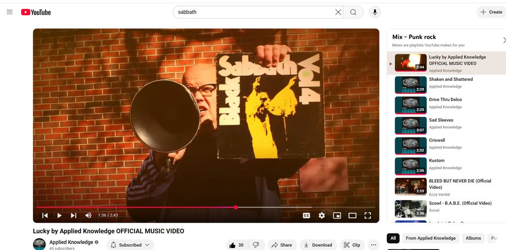 Man yelling into a bullhorn holding a copy of Black Sabbath's Volume 4