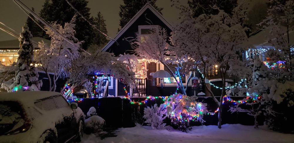 House snow covered and with Christmas lights shining through.