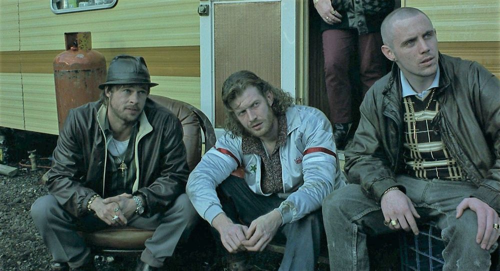 Brad Pitt and a couple other actors from "Snatch" sitting in front of a mobile home.