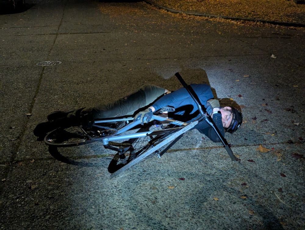 Uhhmmm she is lying on the ground. There is a person lying on the street in gorpy activewear clothing clutching an attractive brakeless fixed gear bicycle, eyes closed. She's got some hips on 'er looks like.