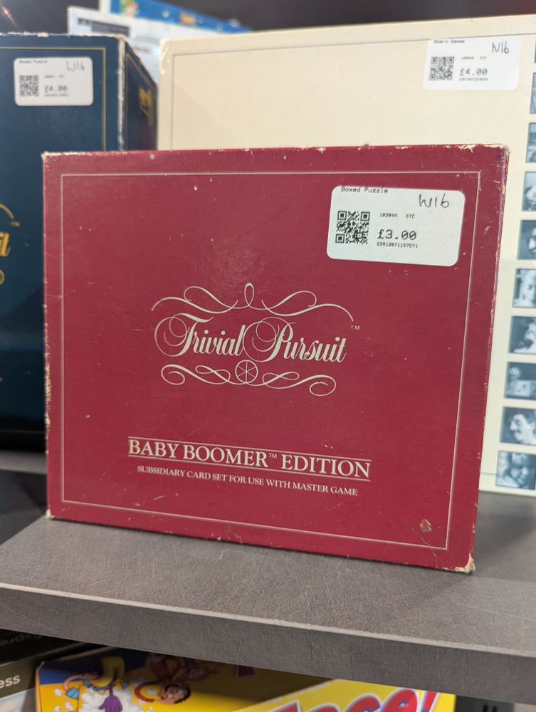 Battered old box of Trivial Pursuit Baby Boomer Edition on a charity shop shelf. It has a price tag of £3.