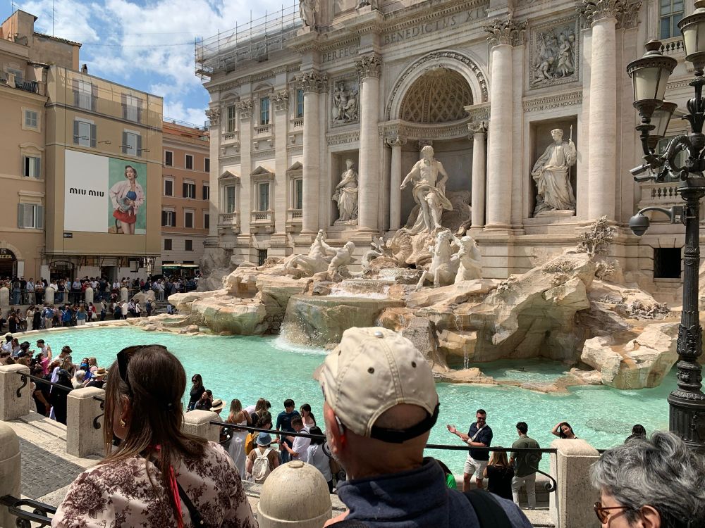 Ivory statues of Trevi fountain in Rome, Italy with aqua blue water. Crowds encircled the perimeter 