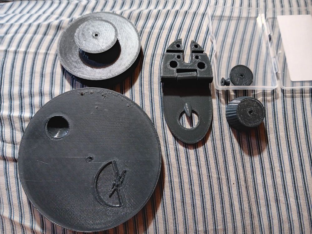 3d printed parts for the Good and Basic Charkha spinning wheel. Top and bottom left are the accelerator wheel and drive wheel, respectively. In the center is the maiden and its base. On the top right is a small clear box with the spindle pulley and guard. Below the box is one of the mounts for the wheels. 

I am so excited to put this together! I just need a base, some 3/32" steel rods, and some nice glue that'll work with plastic and (probably) wood. I'm gonna spin the last of my alpaca on it and make my brother something very nice for his birthday 🥰 he's a treasure.

#spinning #spinnersofbluesky #fiberarts #charkha #charkhawheel #goodandbasic #3dprinting 