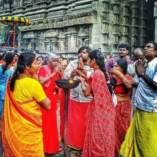 Devotees in vibrant traditional Indian clothing pay obeisance with folded hands before the sacred flame at Arunachaleswar Temple, Tiruvannamalai, Tamil Nadu, India