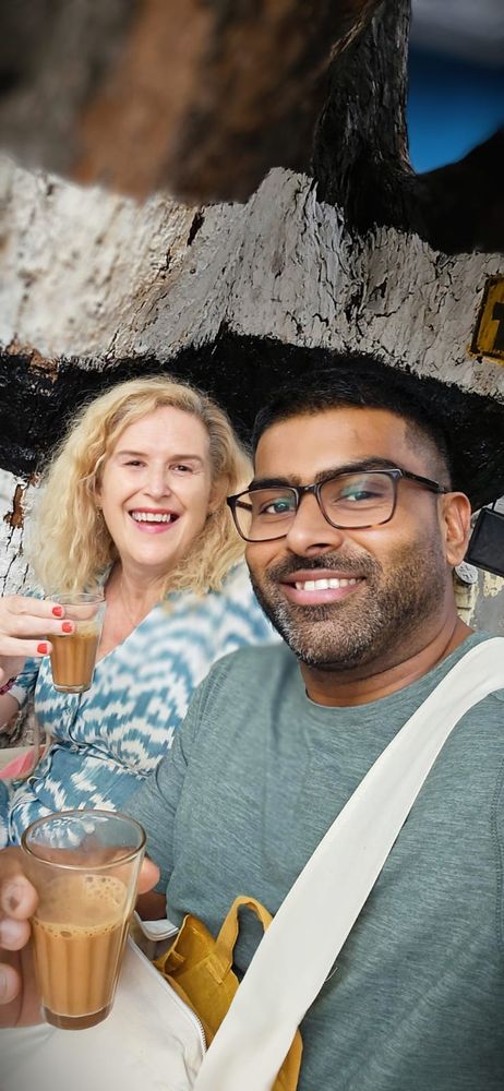 Two friends, one Irish and the other Indian, 'cutting chai' beneath the shade of a tree at a roadside teashop, Tiruvannamalai, Tamil Nadu, India.