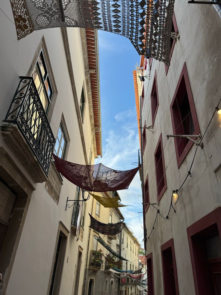 Crochet blankets hanging across a narrow street in Coimbra. 