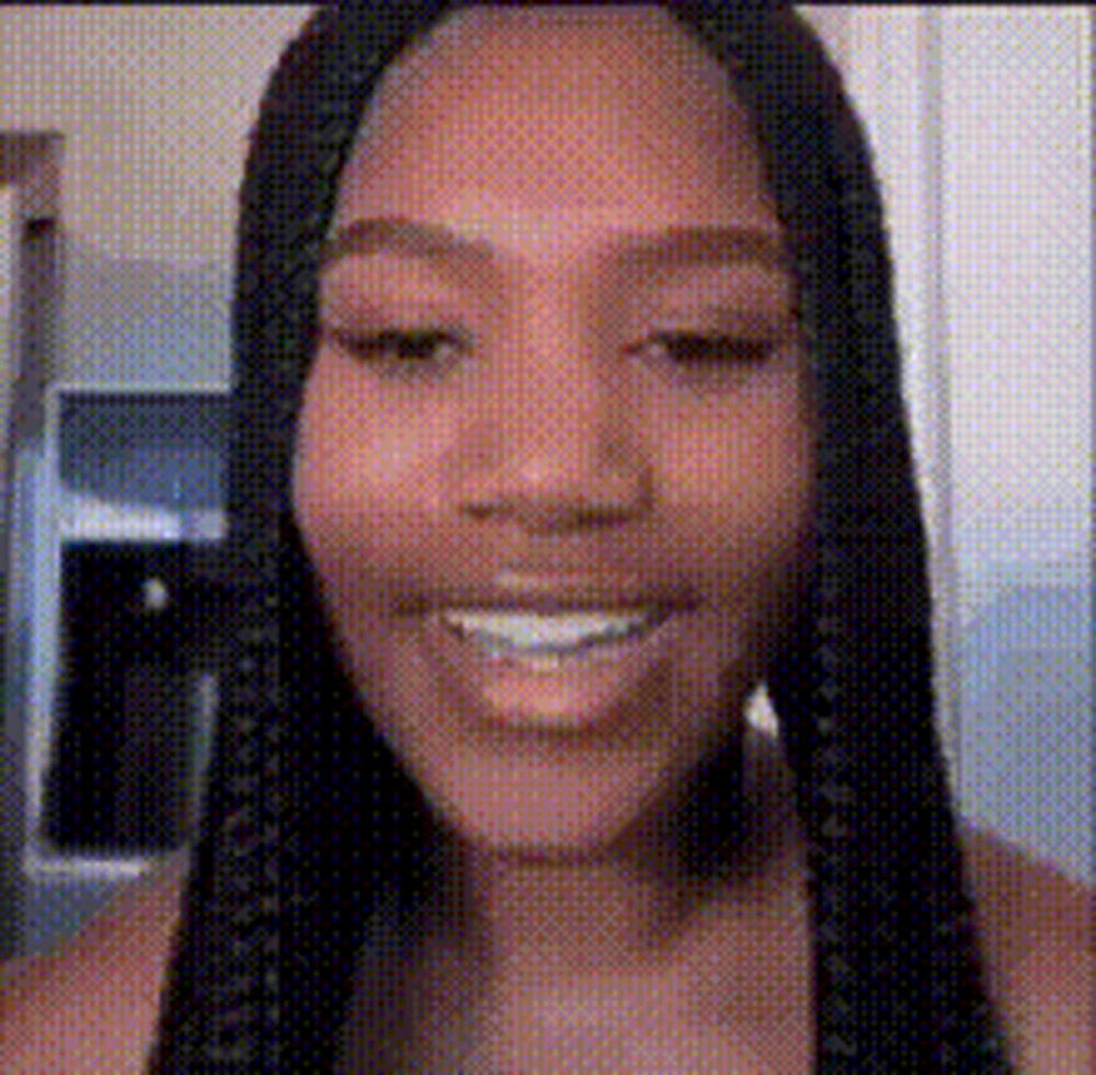 a woman with braids is smiling and looking at the camera in a pixelated image .