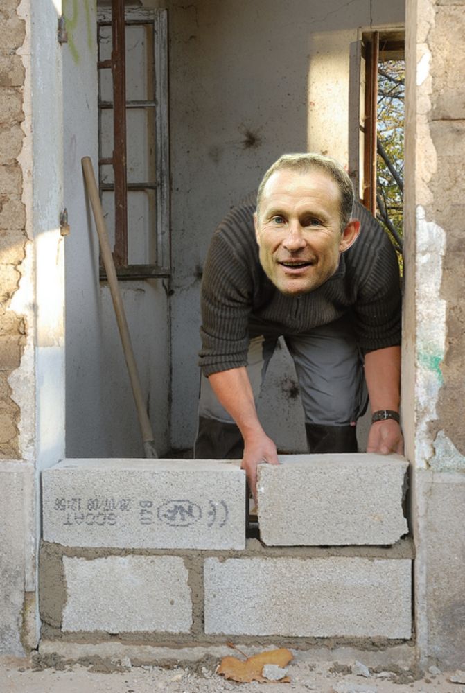 Ouvrier du bâtiment qui pose un parpaing avec la tête de jean pierre Papin