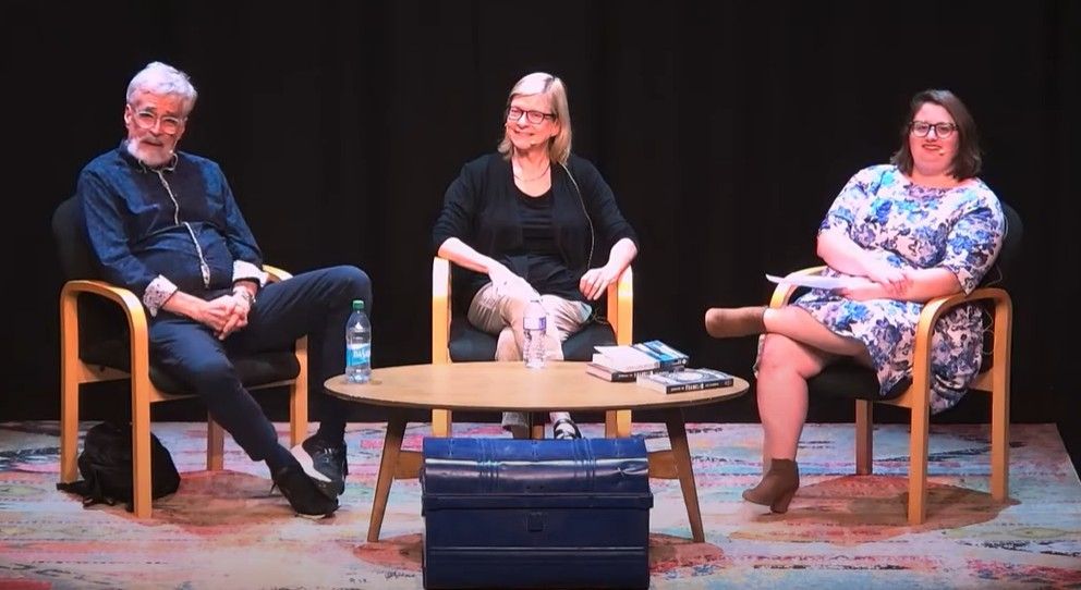 Shows Ken McGoogan, Eve Lazarus and Amanda Farnel on stage behind a table and a blue chest 