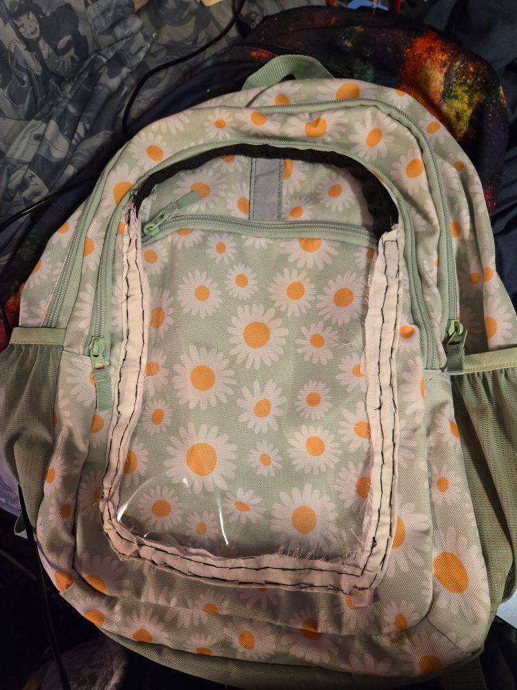 A flower-themed backpack with a transparent pocket sewn to the front