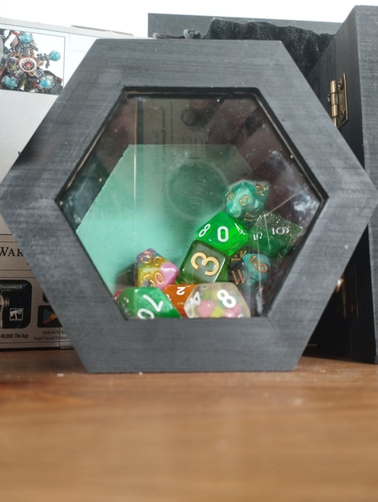 Black hexagon box with acrylic top with dive inside mostly of green. There's a mint green back wall/bottom.