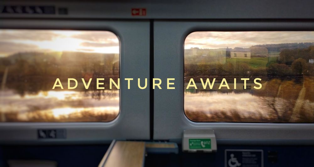 Image of two train windows side by side. Looking out into the countryside a body of water and the sun reflecting into it and shining at the top of the image. Centre of the image reads "Adventure awaits"