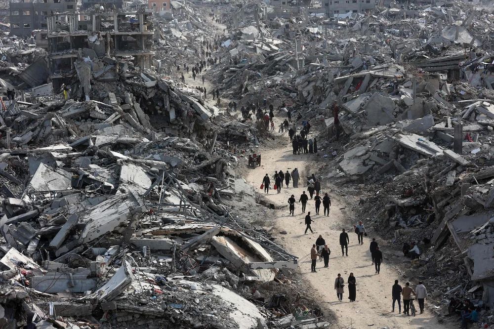 People walking on a narrow road between ruins. 
