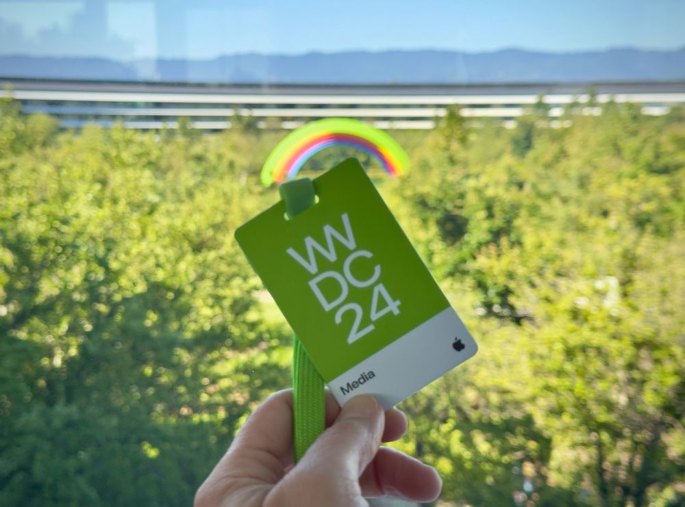 WWDC 2024 badge in front of window looking out on Apple Park