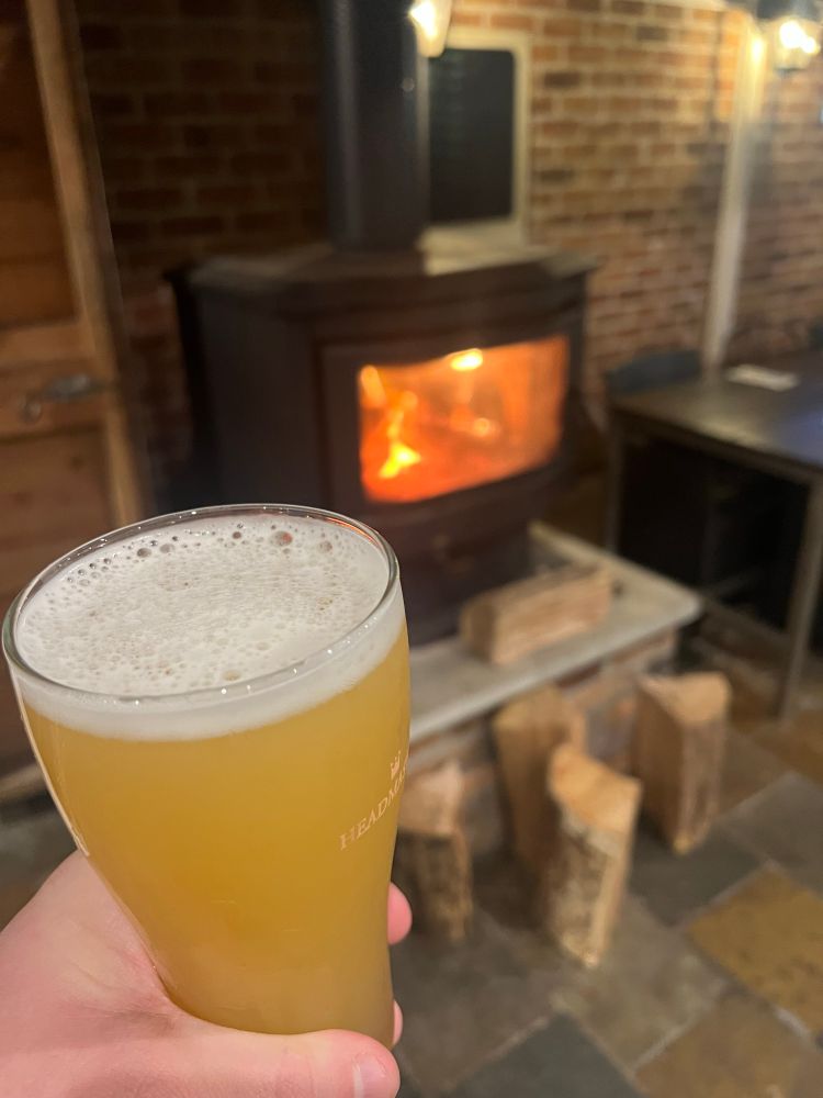 Hand holding a beer in front of a combustion fireplace.
