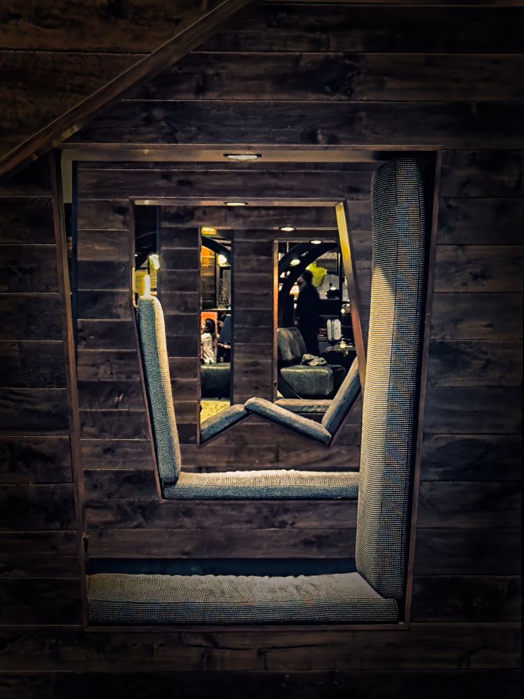 A series of framed perspectives showcasing cushioned seating areas arranged in a receding pattern. The walls are wooden, creating a cozy ambiance. Soft lighting adds warmth to the scene.