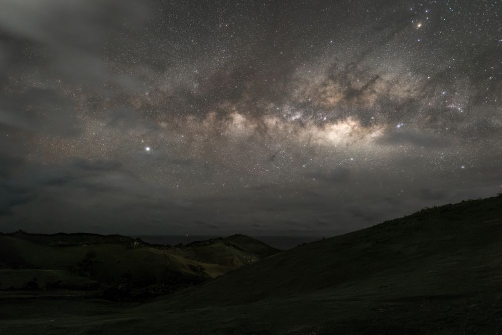 The milky way core over a hilly green landscape