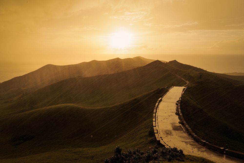Golden sunset over rolling hills with streaks of rain