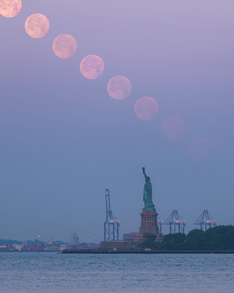 A composite image of a descending moon over the Statue of Liberty eventually becoming obscured by haze from wildfires.