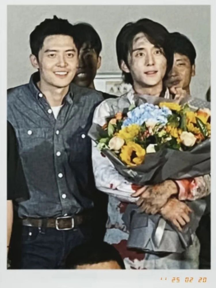 fu xinbo and zhang xincheng both filthy and exhausted looking at the wrap party. in addition steven is covered in blood but holding flowers