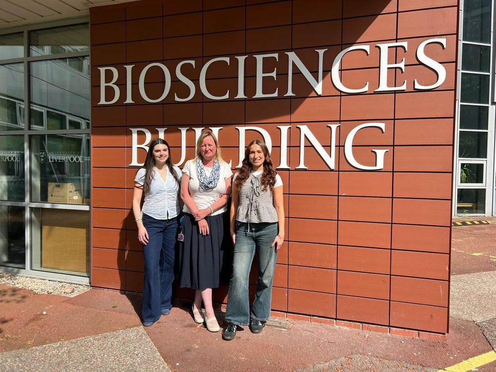 Amelia, Helen and Isobel standing against a brown wall that says Biosciences Building 