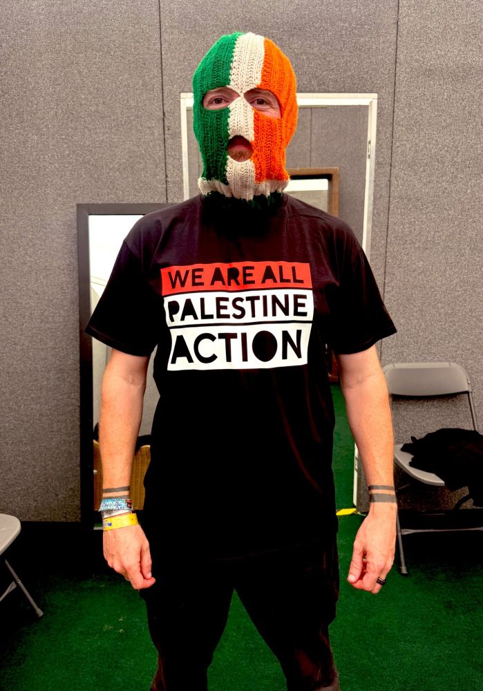 DJ Provai in his trademark tricolour bally, and a t-shirt saying "WE ARE ALL PALESTINE ACTION", an hour before Kneecap plays Glastonbury 2025.