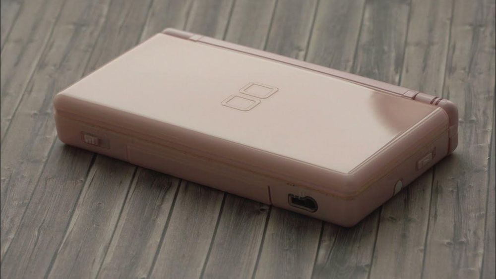 image of a Nintendo DS Lite placed on a wood panel surface.