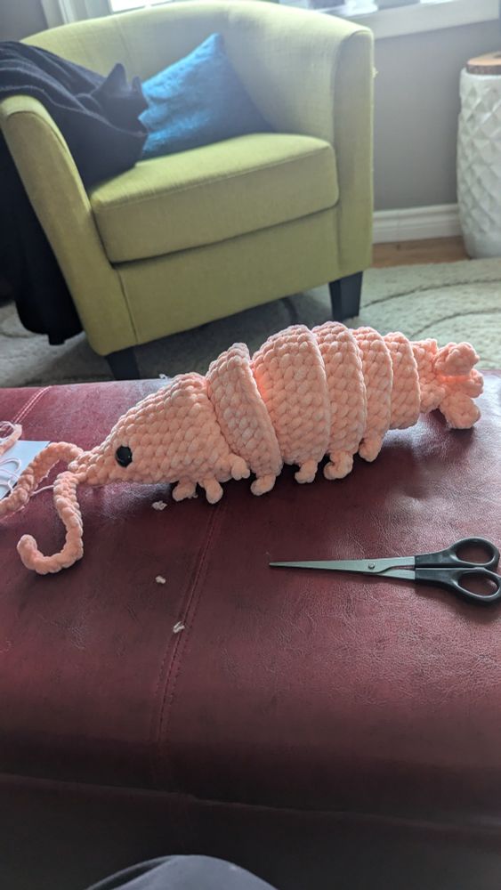 A light coral coloured crocheted shrimp 