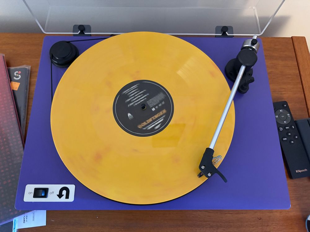 Purple turntable with gold colored record on it.