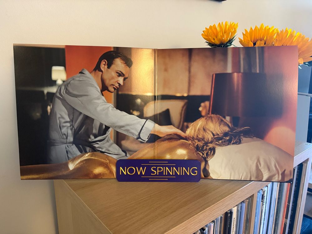 Inside the record sleeve is a still from Goldfinger. James Bond finds Tilly Masterson covered in gold on the bed they previously shared.