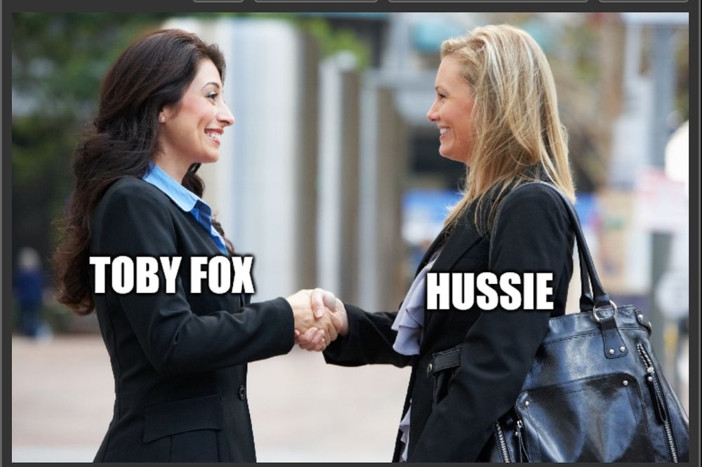 Two women in suits smiling and shaking hands, a brunette labeled "Toby Fox" and a blonde lady labeled "Hussie."