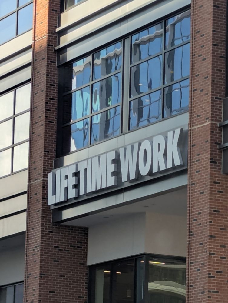 Signage over the door of a high rise building that reads, "Lifetime Work"