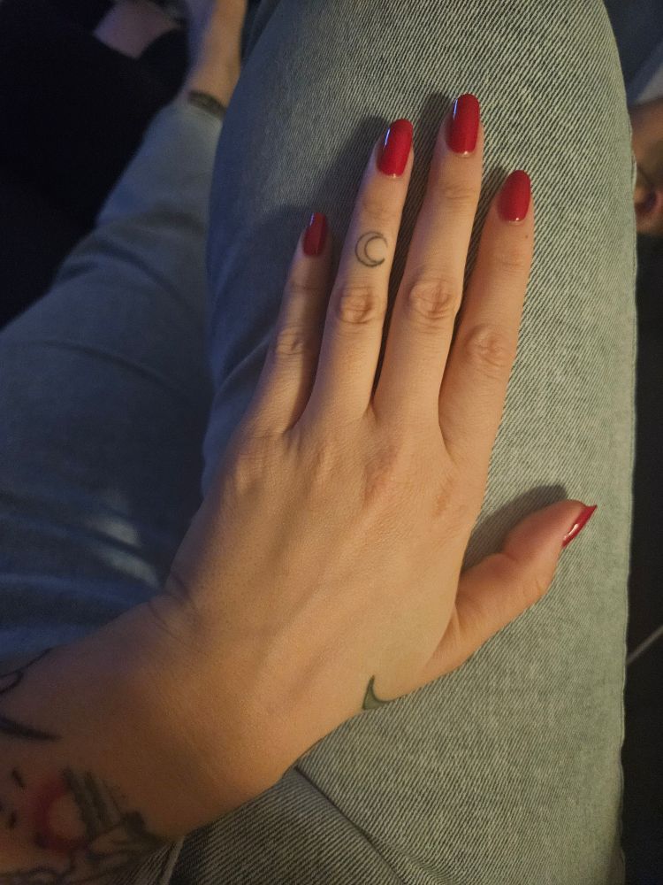 Hand mit rotlackierten Nägeln.