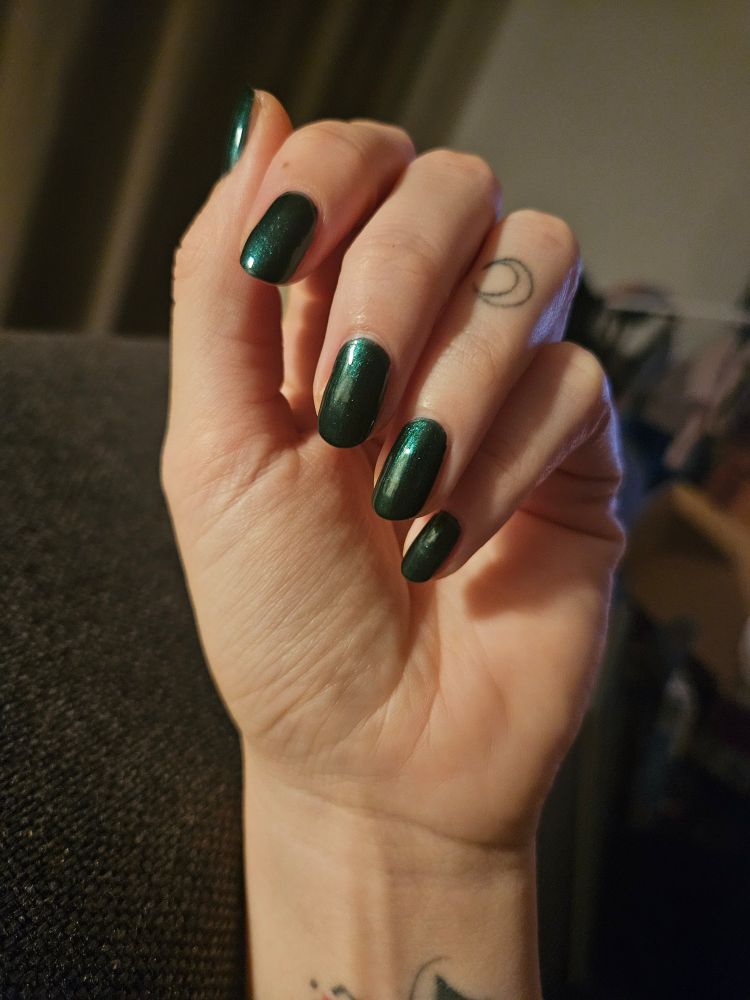 Hand mit grün lackierten Nägeln.