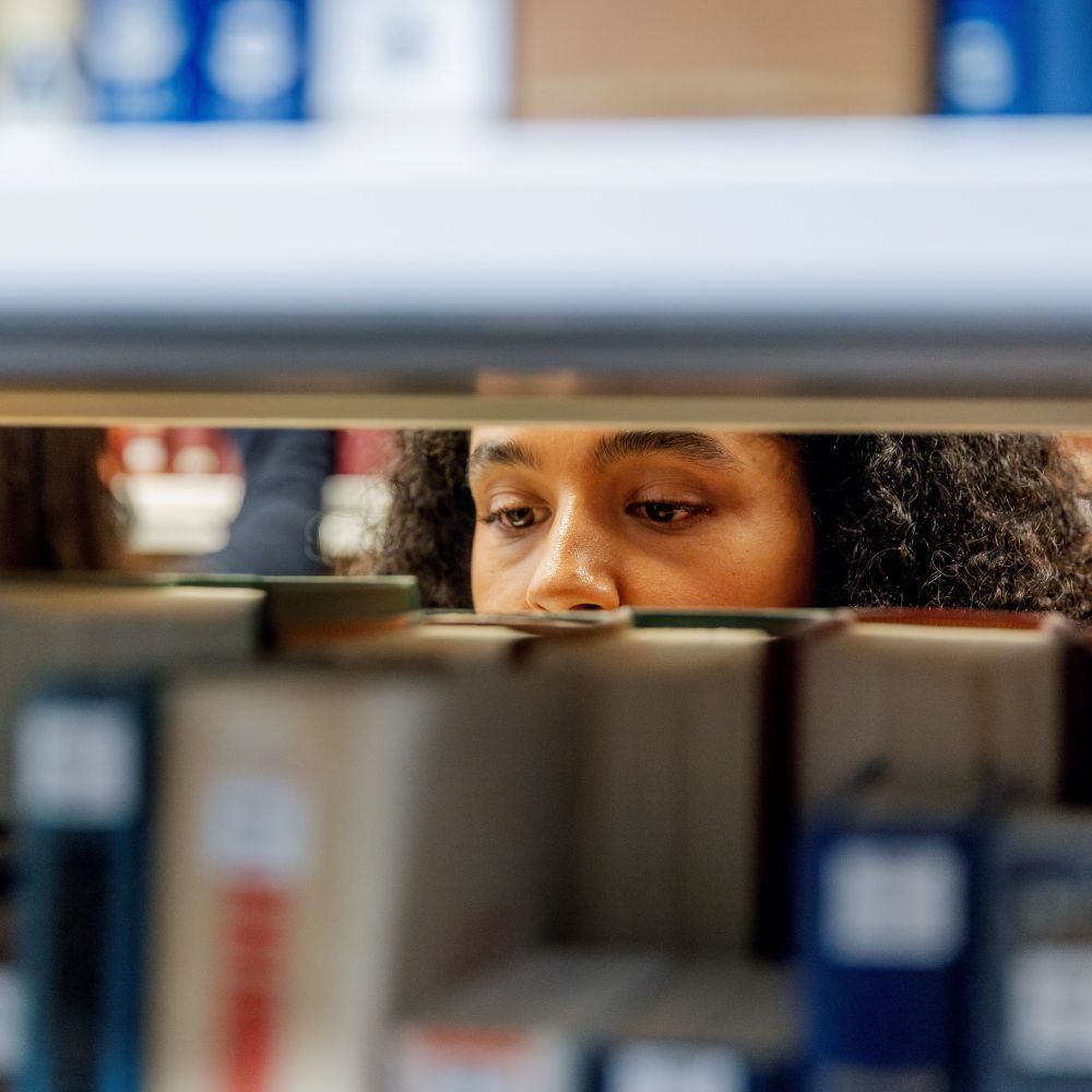 A woman looking at books on a shelf.