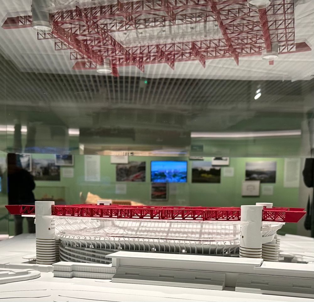 side view of a white and red plastic model of anfield. it is also reflected in the glass above