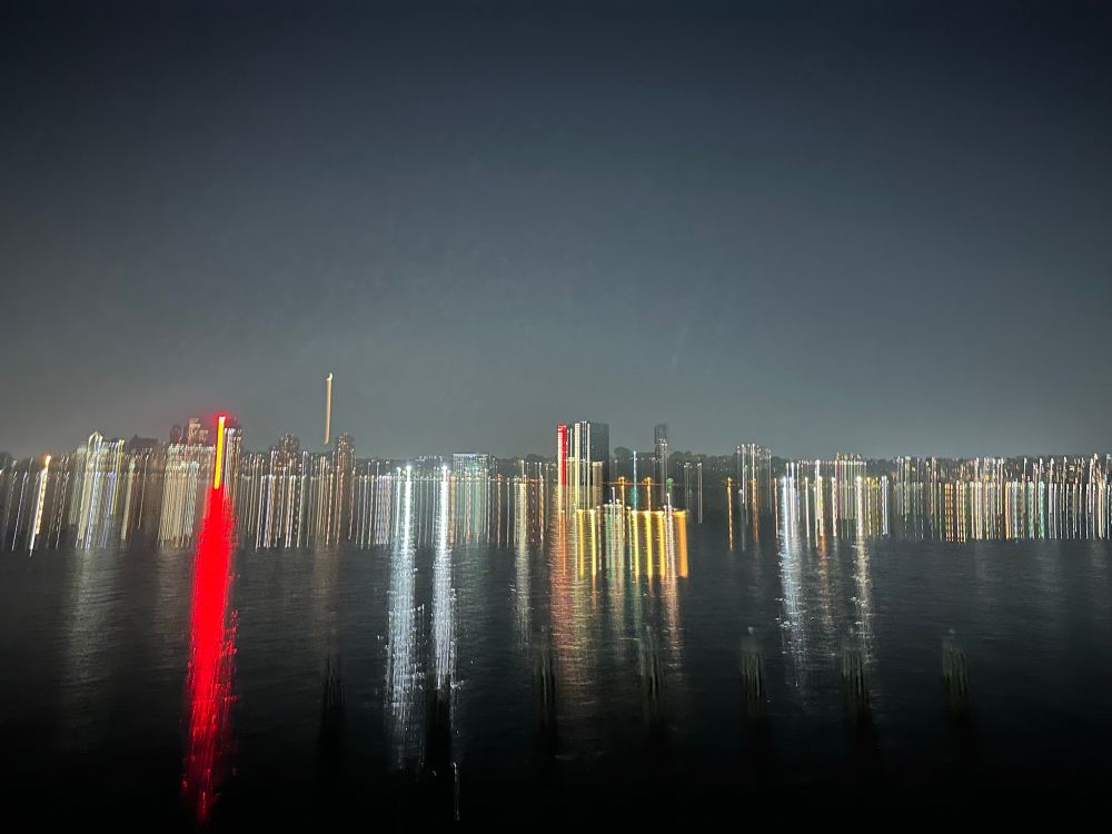cityscape at night with elongated streaks of red, yellow, and white lights