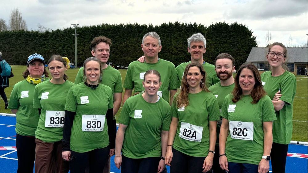 Group of runners stand on a running track in green t-shirts