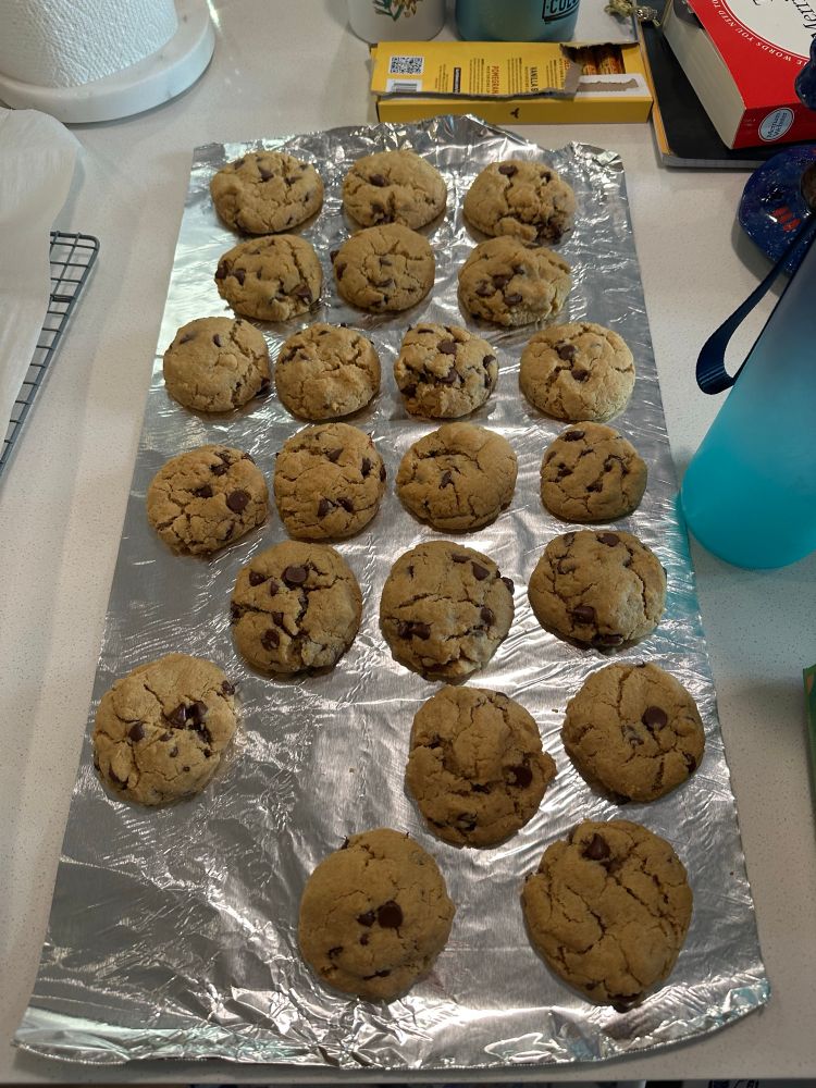 Peanut butter chocolate chip cookies on a sheet of aluminum foil to cool