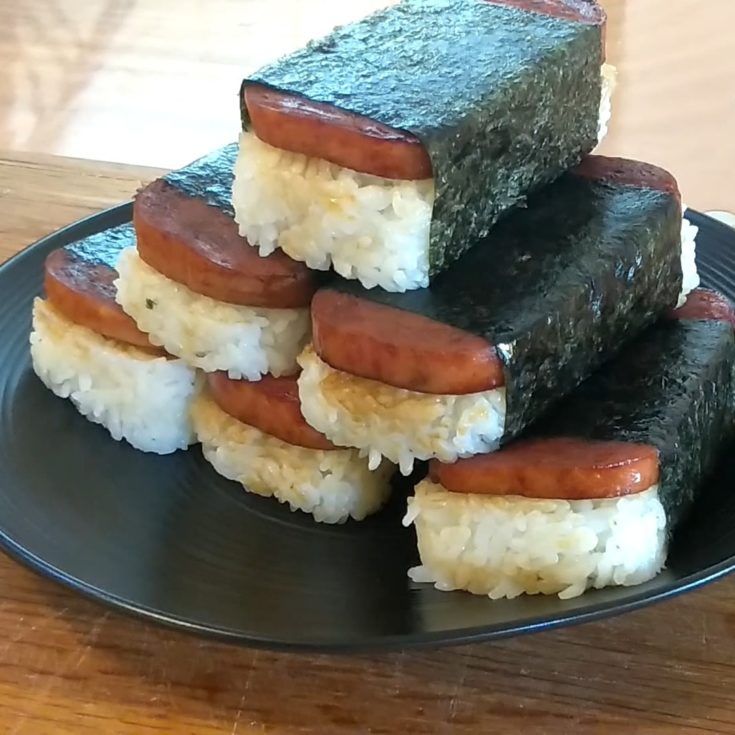 Spam Musubi stacked on a black plate.