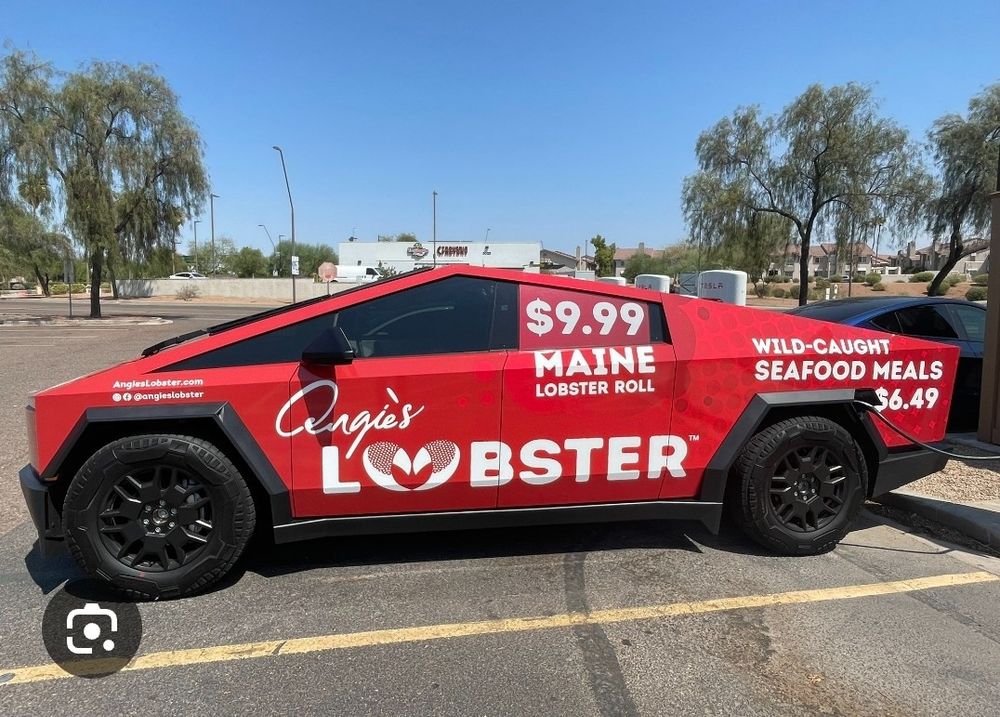 A red cybertruck covered in ads for cheap seafood in Arizona.