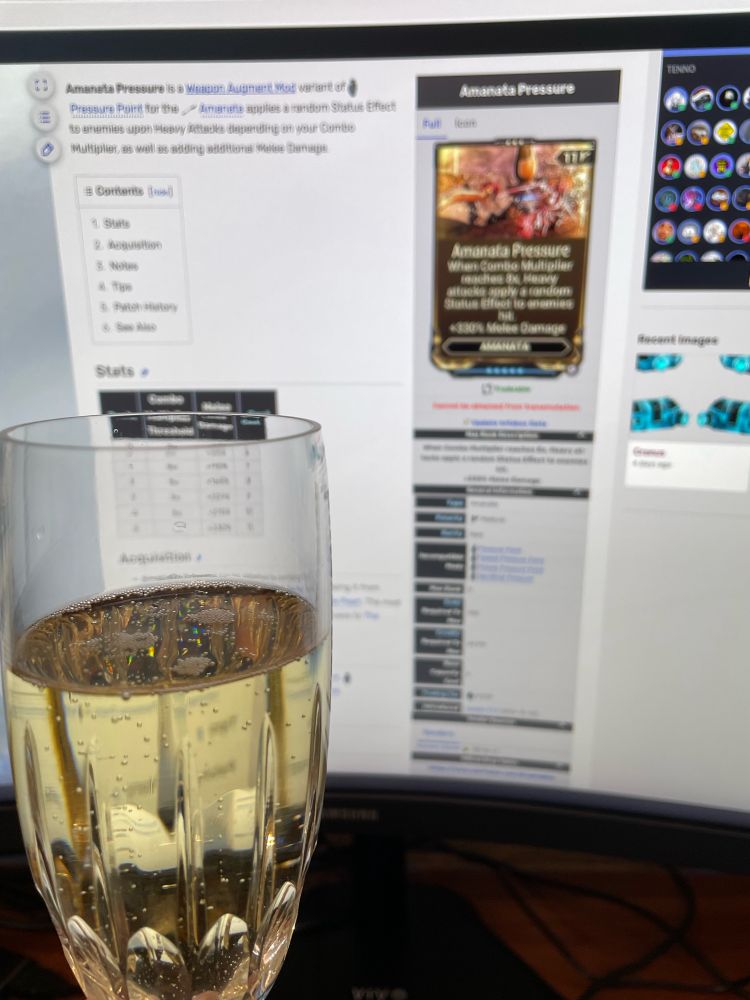 A glass of champagne held in front of a curved pc monitor. The monitor is displaying the Amanata Pressure page of the Warframe wiki