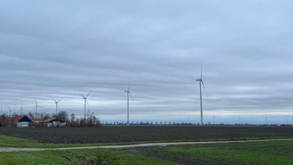 Windmolens op een rij onder lichtbewolkte lucht in Flevoland 