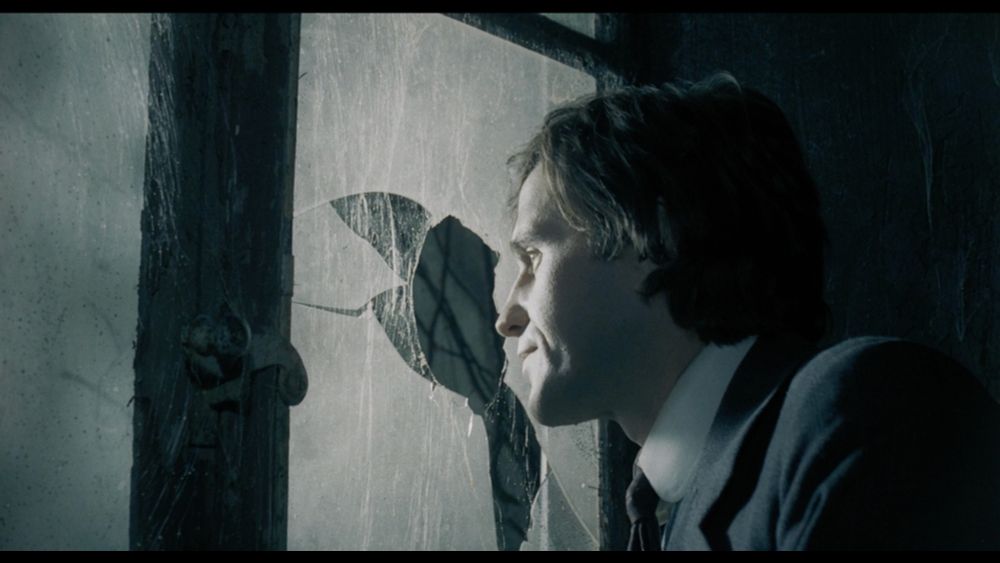 A man looks out of a broken window