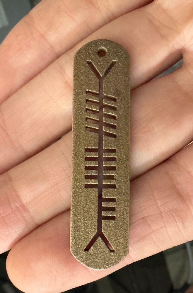 Bronze infused steel pendant with three letters in ogham , consisting of lines, half lines, and slanted lines. 